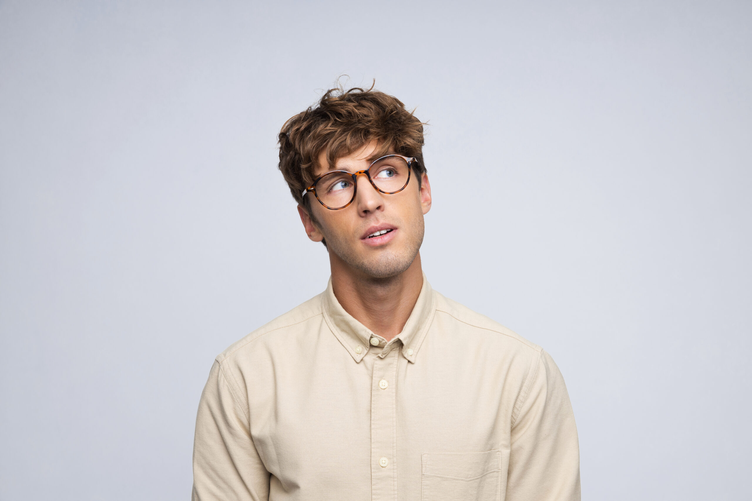 Portrait of surprised young men wearing beige shirt looking away
